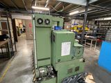 a large green machine in a warehouse with a trash bag