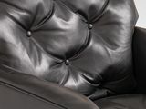 the back of a black leather chair with buttons on the arms
