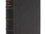 un vieux livre à la couverture noire posé sur une surface blanche