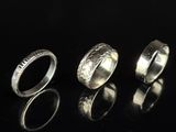 three different types of silver rings on a black surface