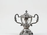 an antique silver plated trophy on a stand on a white background