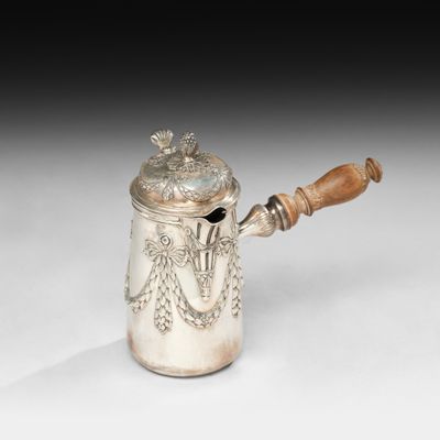 une cafetière en argent avec une poignée en bois sur une surface blanche