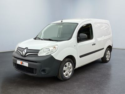 La camionnette blanche est garée dans une grande pièce au sol noir.