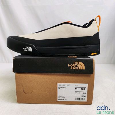 Les chaussures The North Face sont posées sur une boîte, sur une surface blanche.