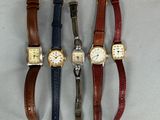 quatre montres différentes sont alignées sur une surface blanche