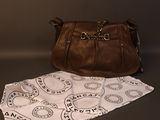 brown leather purse on a table next to a white napkin