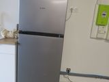 a silver refrigerator in a kitchen with a microwave on top of it