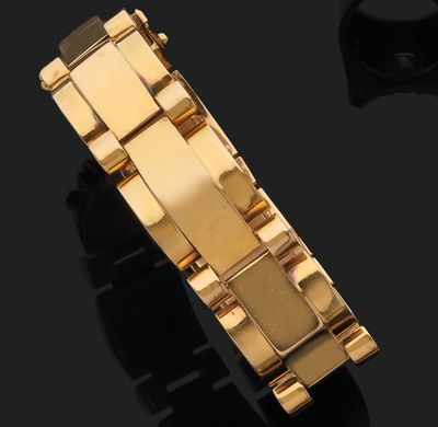 gros plan d'un bracelet en or sur une surface noire