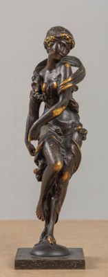 statue en bronze représentant une femme tenant un oiseau sur une table en bois