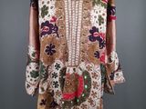 une robe posée sur un mannequin, ornée de fleurs et de feuilles