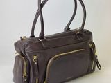 sac à main en cuir marron avec des fermetures éclair dorées sur fond blanc