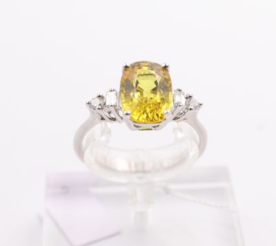 a close up of a yellow sapphire and diamond ring on display