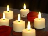 des bougies allumées posées sur une table en bois, ornée de feuilles et d'une rose rouge