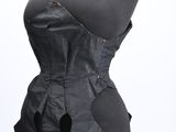 black leather corset with a bow tie on a mannequin