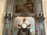une horloge posée sur la cheminée, avec un tableau accroché au mur