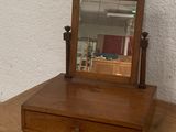 a small mirror on top of a wooden dresser