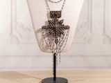 Collier avec une croix en perles, présenté sur un mannequin devant un fond blanc
