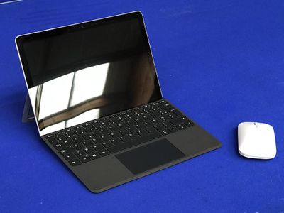 un ordinateur portable et une souris posés sur une table bleue