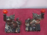two figurines of a cat and a cat holding a ball