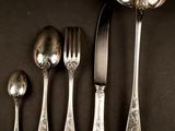 five silver spoons and two silver spoons on a table