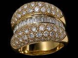 a gold ring with baguets and diamonds on a black background