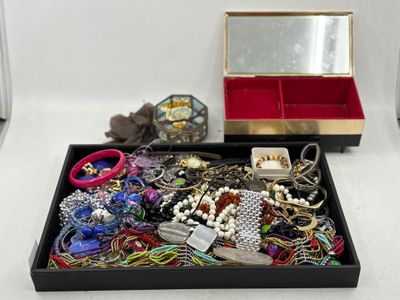 une boîte noire remplie de bijoux variés, posée sur une surface blanche