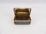 a small silver box with a gold lid on a white surface