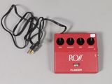 a red guitar pedal sitting on a table next to a cord