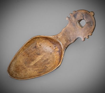 an old wooden spoon with a wooden handle on a gray surface
