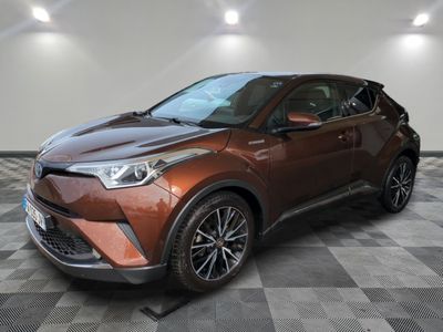 une Toyota C-HR marron garée dans une pièce au sol à damier
