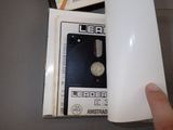 a hand that is holding a white object in front of a box