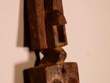 an old wooden sculpture of a face on a wooden stand