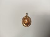 a close up of a gold pendant with a pearl in the center
