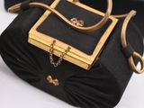 a black purse with a gold handle on a table