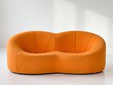 an orange curved sofa sitting on top of a white floor next to a window