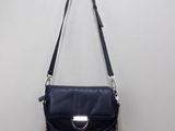 un sac à main noir accroché au mur, à côté d'un mur blanc