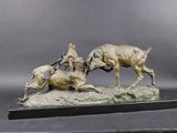 bronze sculpture of two rams fighting each other on a rock