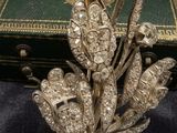 silver plated brooch with flowers and leaves on a black cloth
