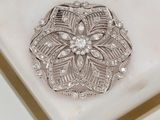 a silver brooch on a white marble surface