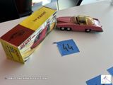 une petite voiture rose posée à côté d'une boîte sur une table