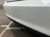 a white car parked in a parking lot with a sticker on it ' s bumper