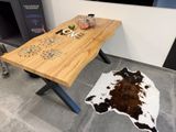 une table en bois avec un tapis en peau de vache posé au sol