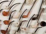 many different types of smoking pipes lined up on the wall