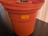 un seau en plastique orange contenant une brosse à dents, posé sur une table