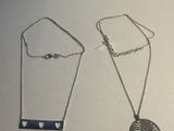 deux colliers en argent posés sur une surface blanche, ornés d'un pendentif en forme de cœur