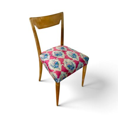 une chaise en bois dont l'assise est ornée d'un motif rose et bleu
