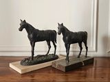two statues of horses standing on top of a wooden table