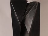 a black sculpture of a triangular shaped object on a white surface