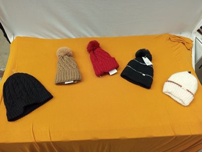 Plusieurs chapeaux sont posés sur une table devant un fond blanc.