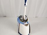 une brosse de toilettes bleue et blanche posée sur les toilettes